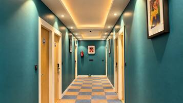 Een hotelgang met blauwgroene muren, geruit tapijt en deuren met de nummers 202.