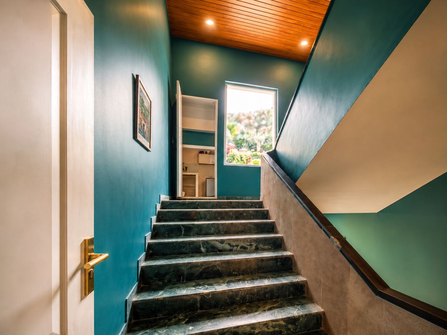 Escada com corrimão de madeira e vista para um quarto com janela.