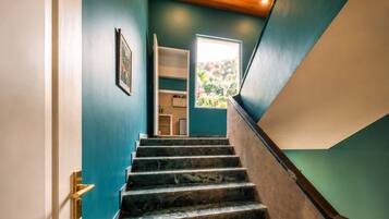 Escada com corrimão de madeira e vista para um quarto com janela.