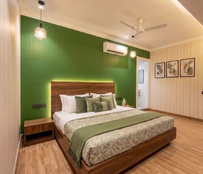 Un dormitorio con pared verde, estructura de cama de madera, ventilador de techo y unidad de aire acondicionado.