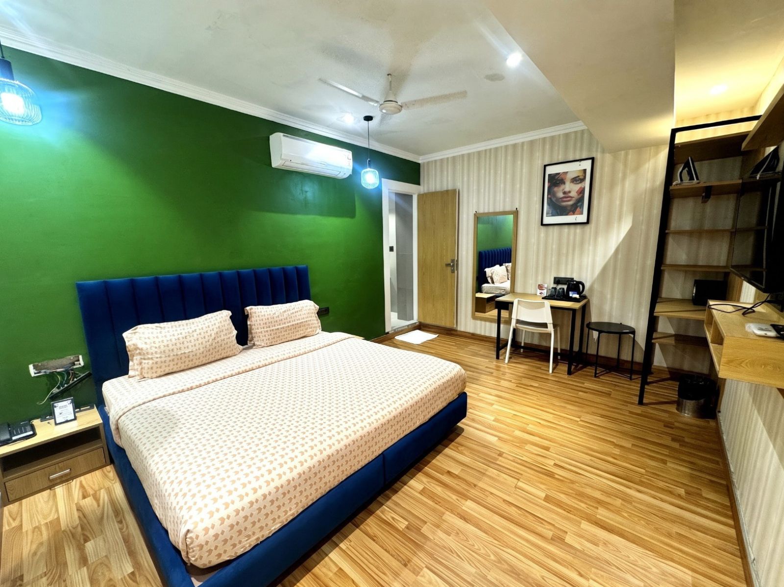 A hotel room with a bed, desk, chair, and a ceiling fan.