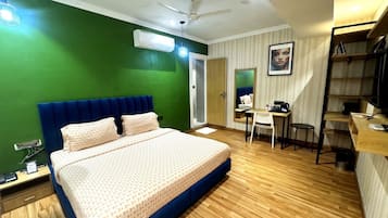 Habitación de hotel con cama, escritorio, silla y ventilador de techo.