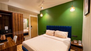 A hotel room with a large bed, a desk, a wardrobe, and a green accent wall. - asar Connaught Place by Orion Hotels (New Delhi)