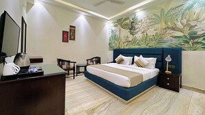 A hotel room with a bed, a desk, a chair, a coffee maker, and a nightstand with a lamp. - asar Connaught Place by Orion Hotels (New Delhi)