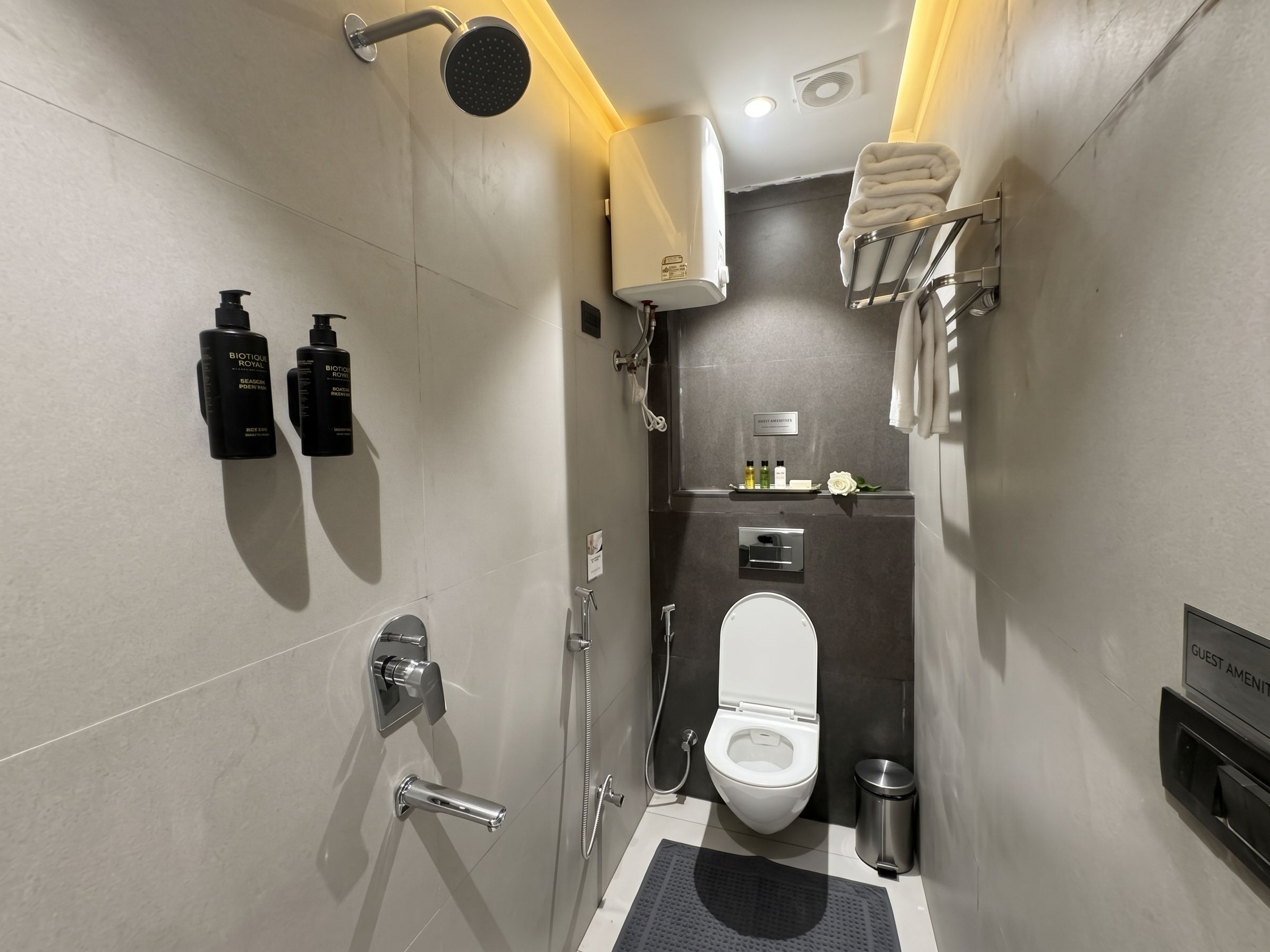 A modern bathroom with a shower, toilet, and a towel rack.