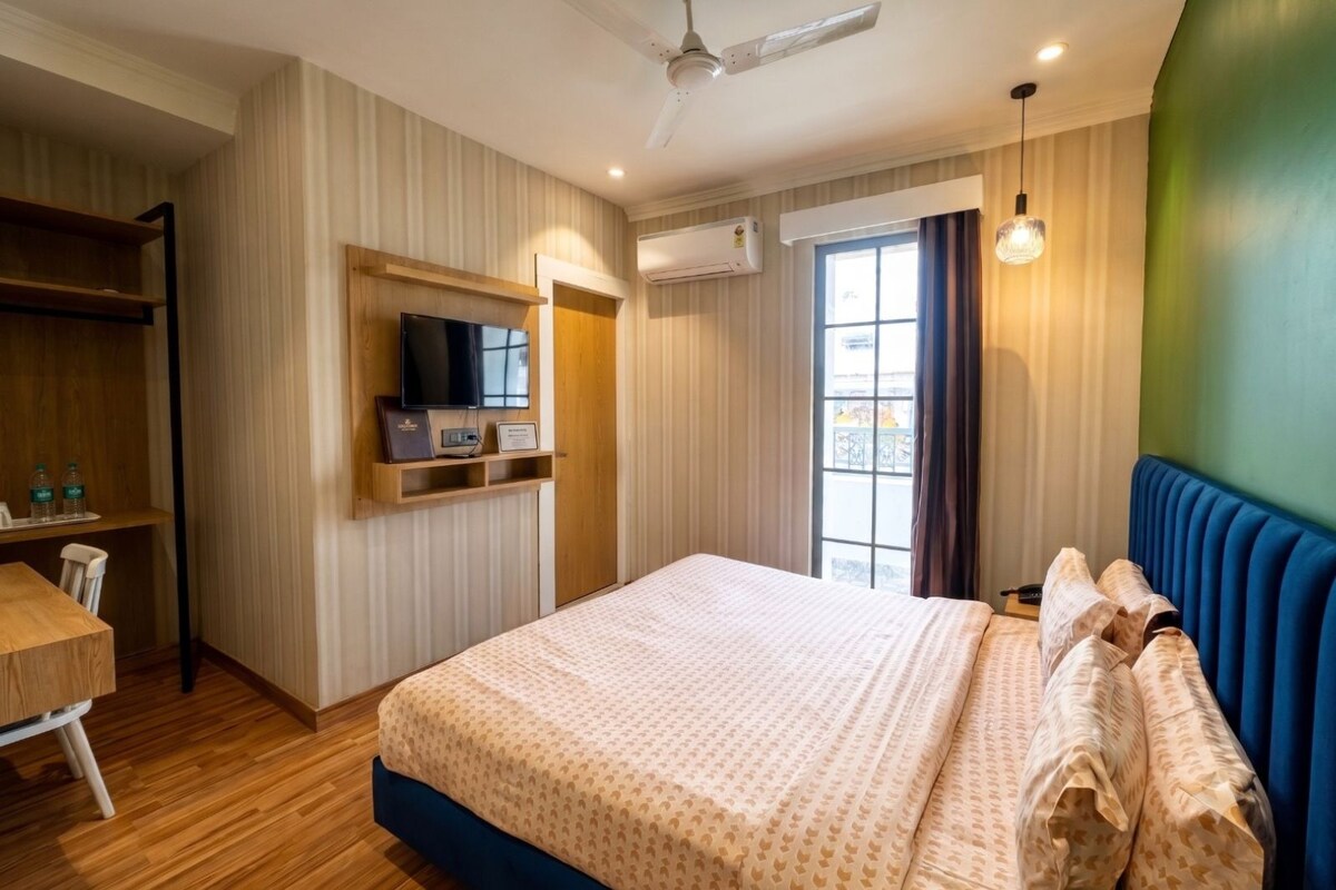A hotel room with a bed, a desk, a television, and a window.