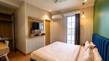 A hotel room with a bed, a desk, a television, and a window.