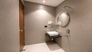 Un baño moderno con un lavamanos rectangular, un cabezal de ducha de mano y un espejo redondo.