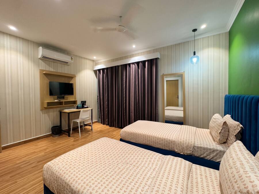 A hotel room with two beds, a desk with a chair, a television, and a mirror.