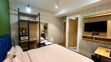 Een hotelkamer met een bed, een bureau, een televisie, een kledingkast en een spiegel.