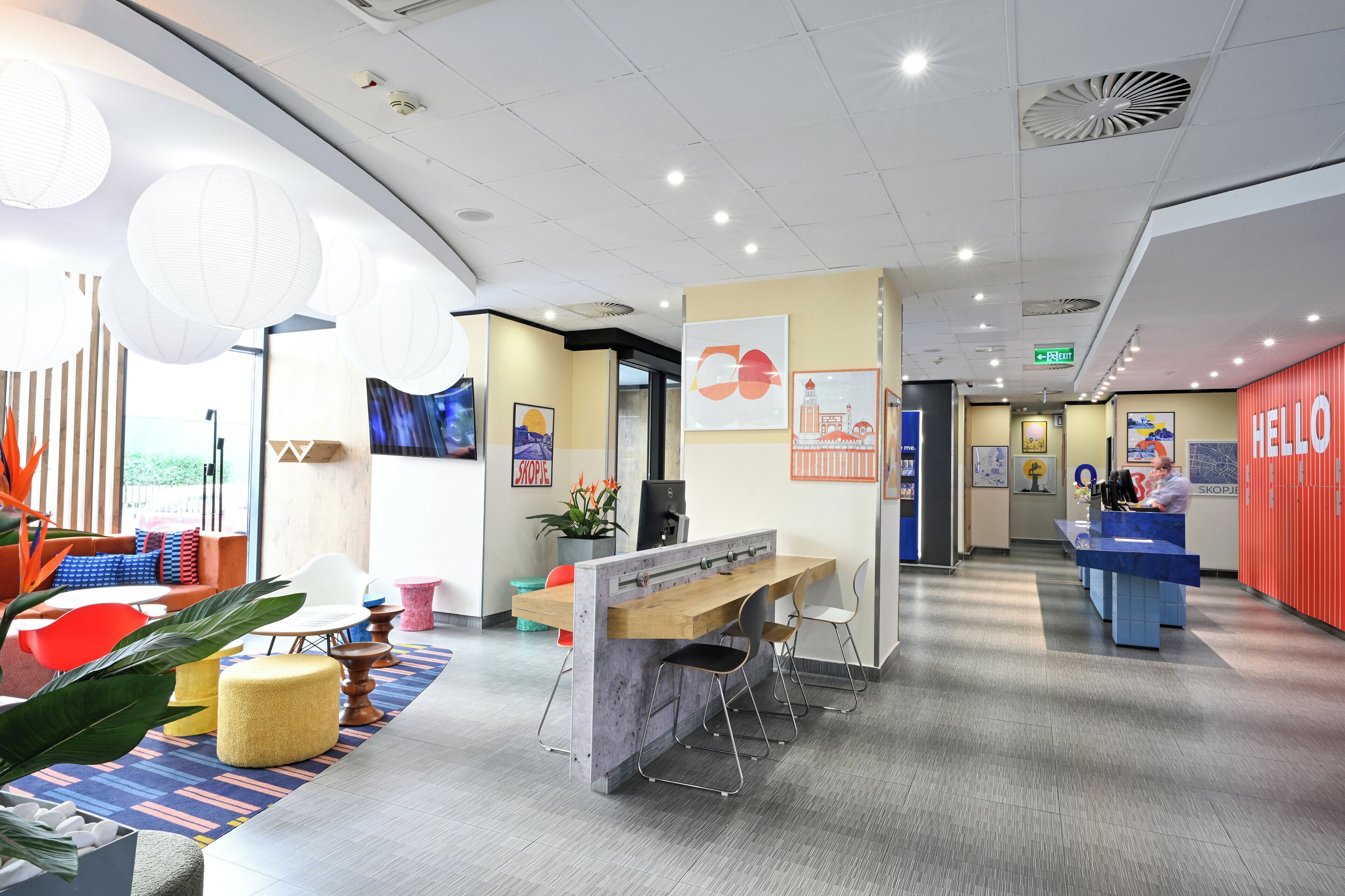 A modern hotel lobby with a reception desk, seating area, and artwork on the walls.