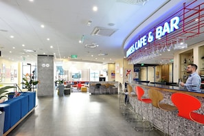 A modern bar area with a counter, bar stools, and a neon sign. - Holiday Inn Express Skopje City Centre (Skopje)