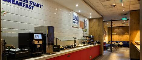 A breakfast area with a counter, coffee machines, and a menu display.