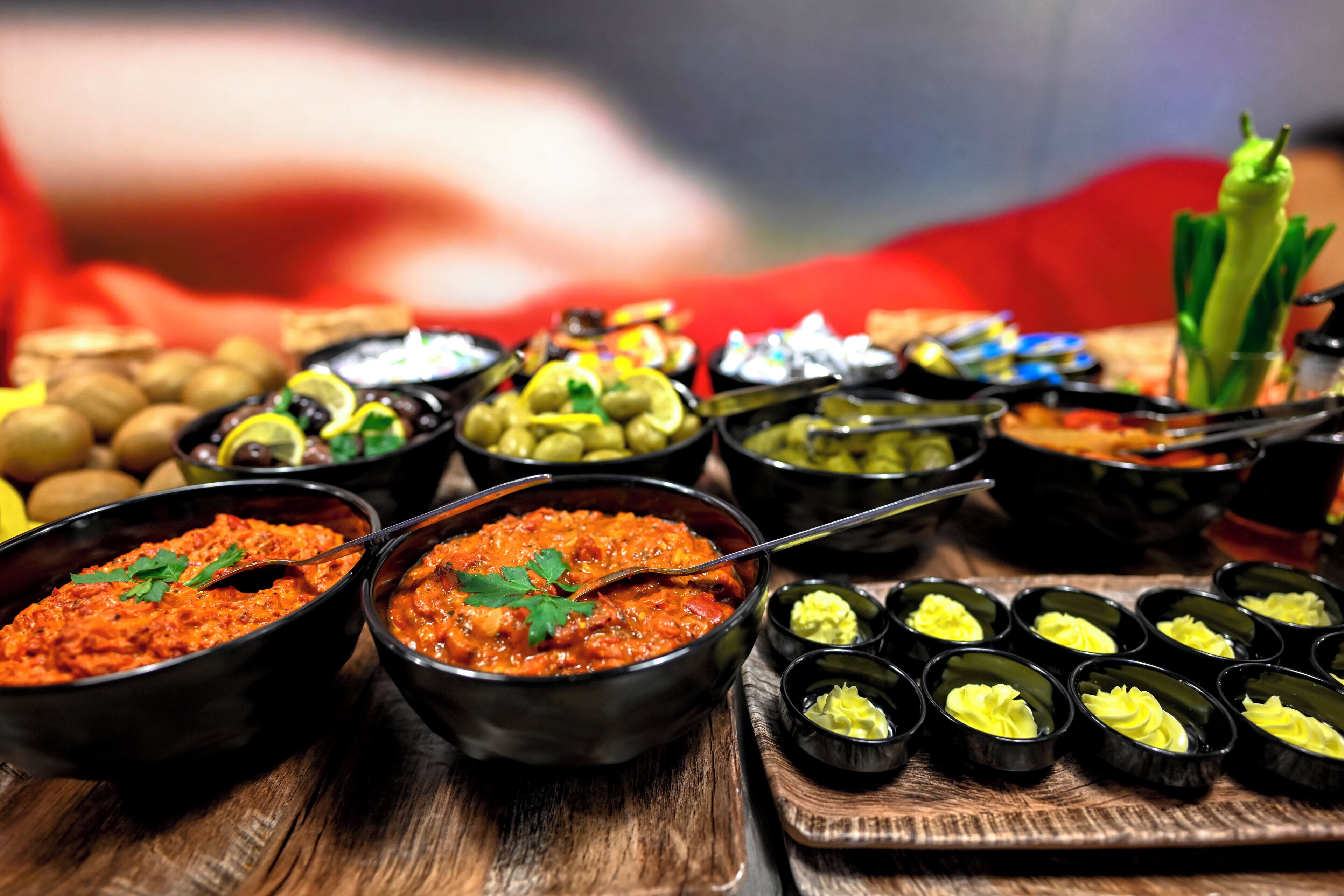 A variety of food dishes in black bowls on a wooden table.
