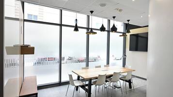 Ett konferensrum med ett stort bord, stolar, hängande lampor och stora fönster.