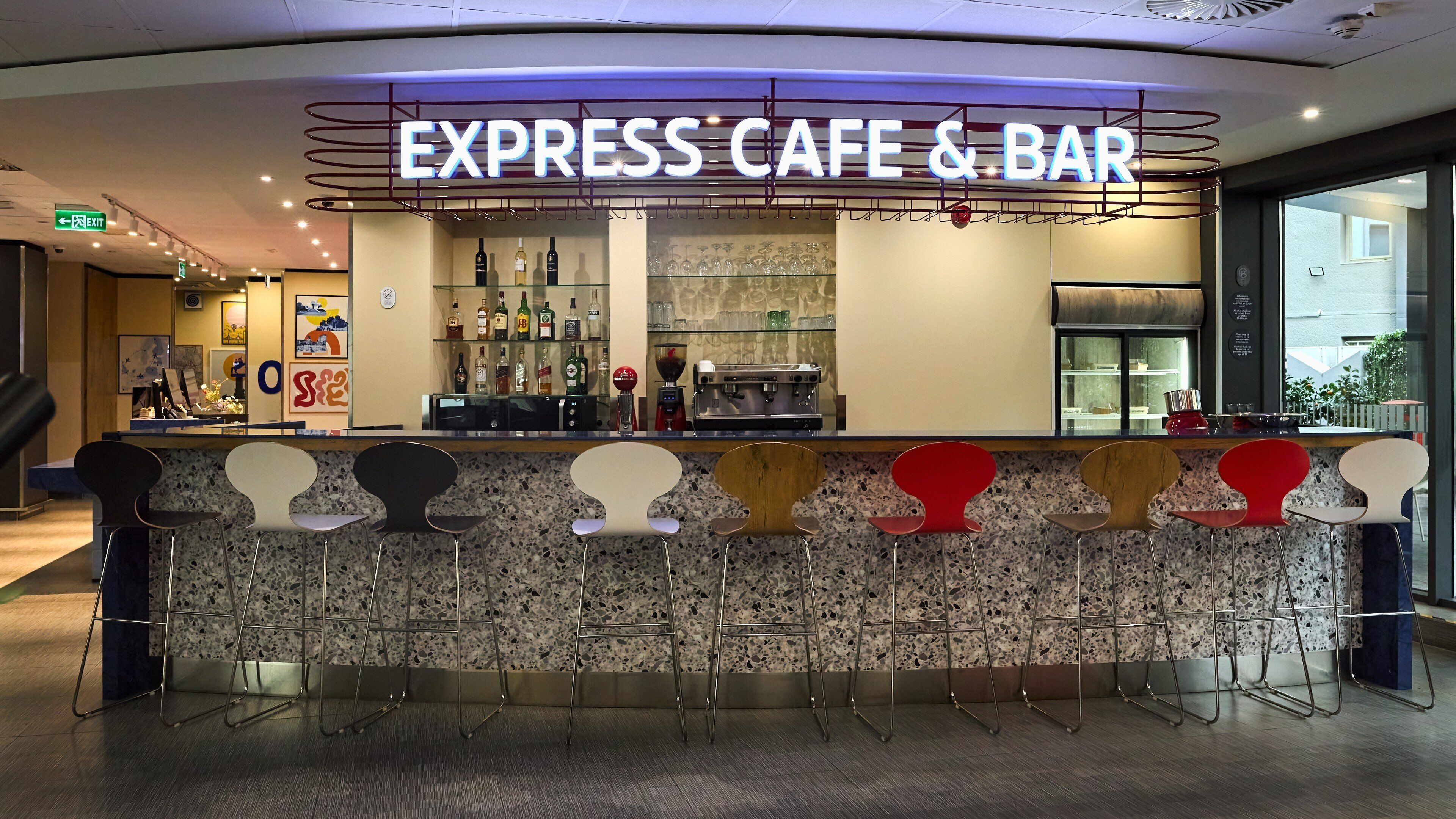 A bar area with a sign reading 'EXPRESS CAFE & BAR,' a counter with a coffee machine, and a variety of chairs.