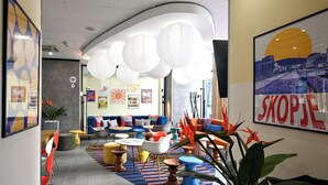 Een modern interieur met zithoeken, een receptiebalie en een groot ingelijst poster aan de muur.