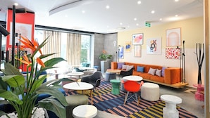 Een moderne lounge met zitplaatsen, tafels en kunstwerken aan de muren.