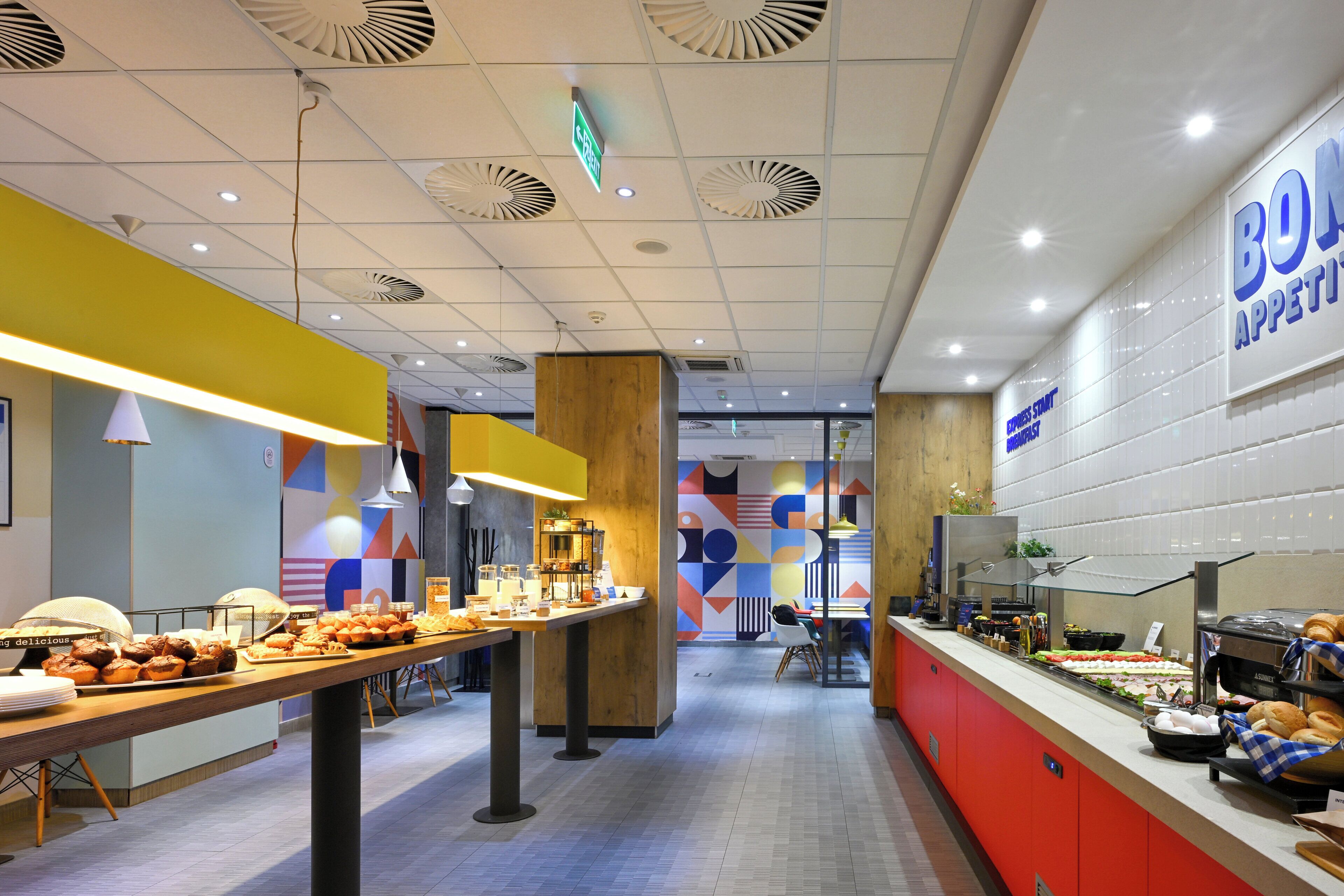 A buffet area with food items, a sign for 'BON APPETIT,' and a counter with a coffee machine.