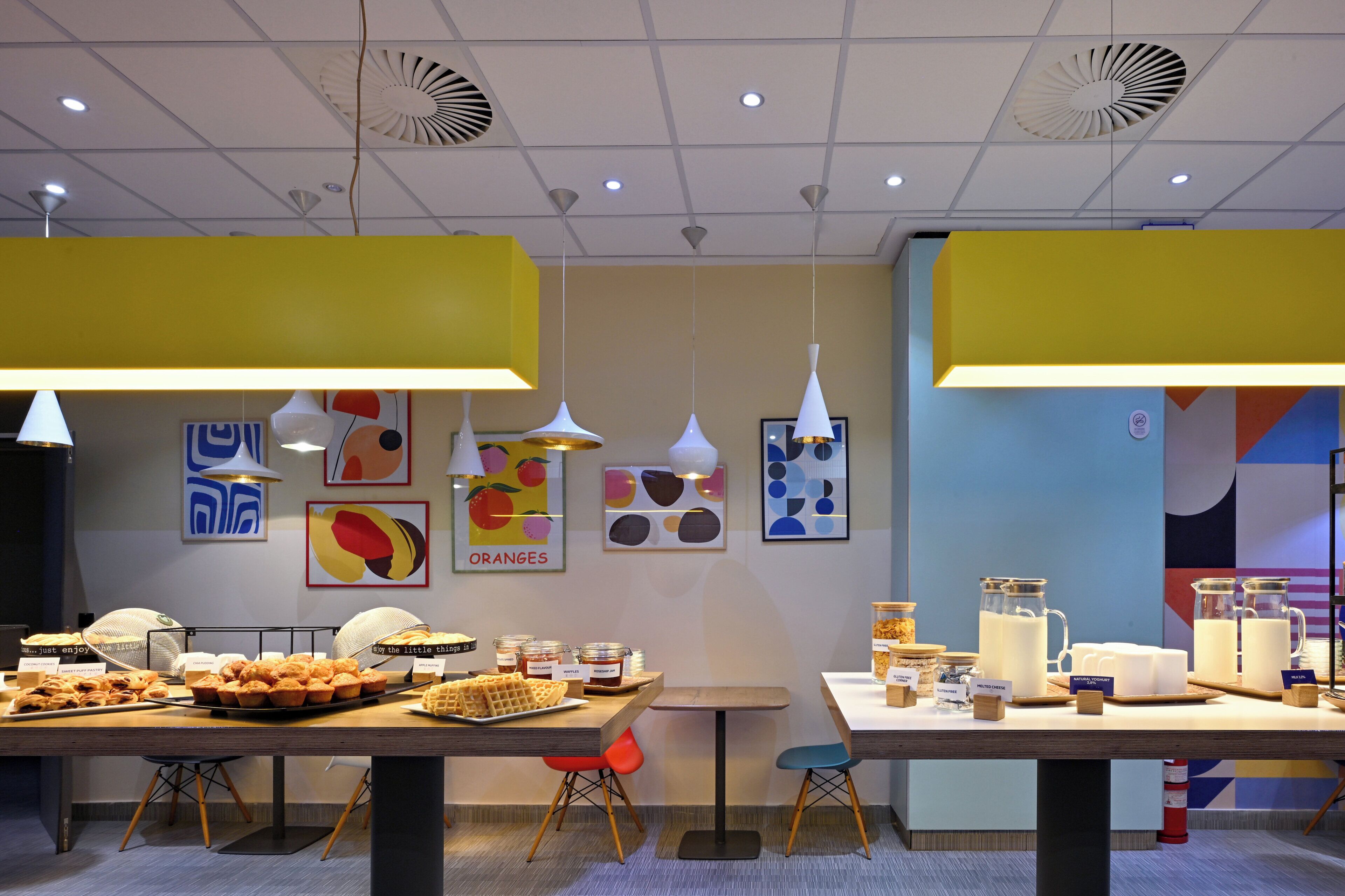 A modern dining area with a buffet setup, including various food items and decorative wall art.