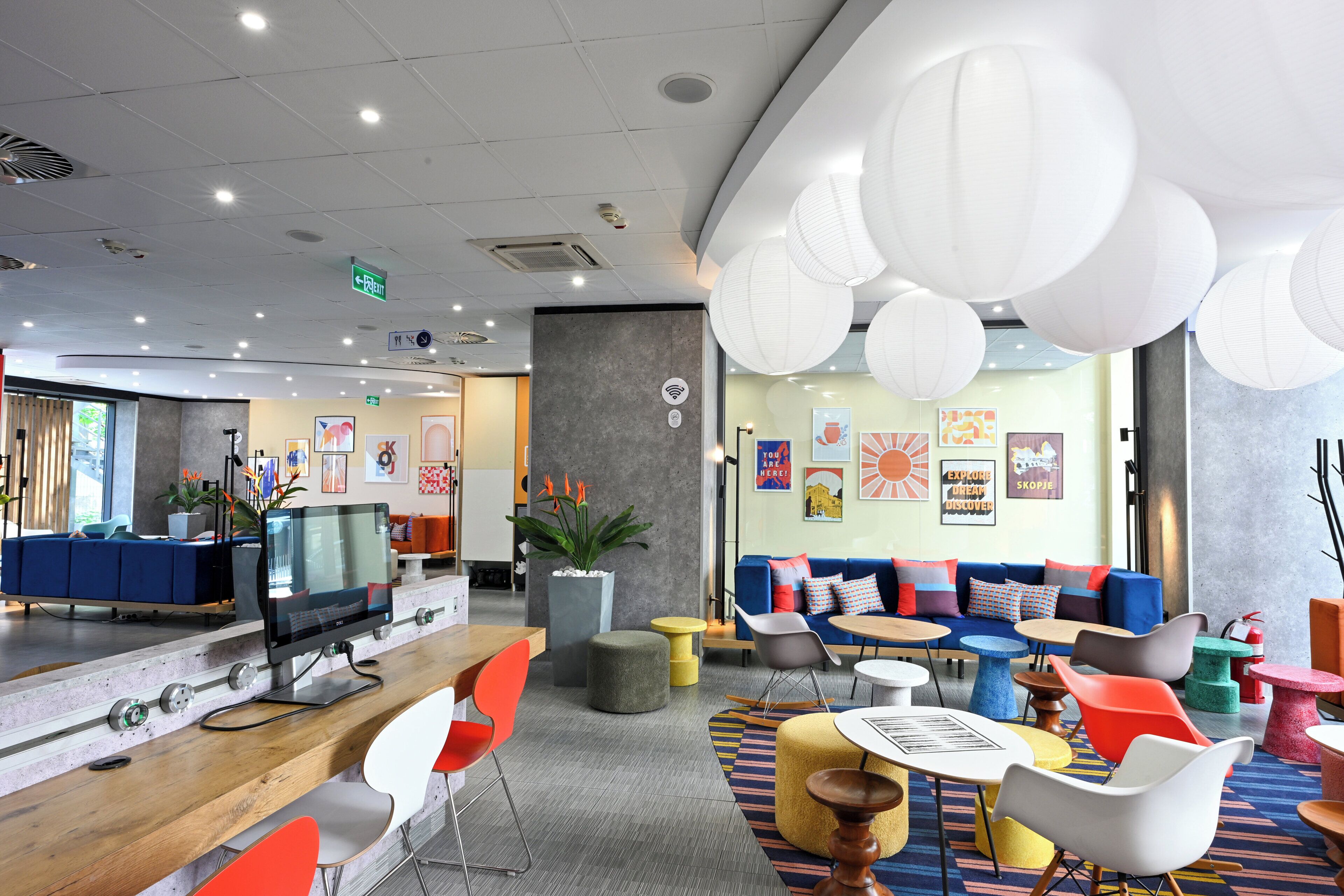 A modern lounge area with seating, a reception desk, and a large screen.