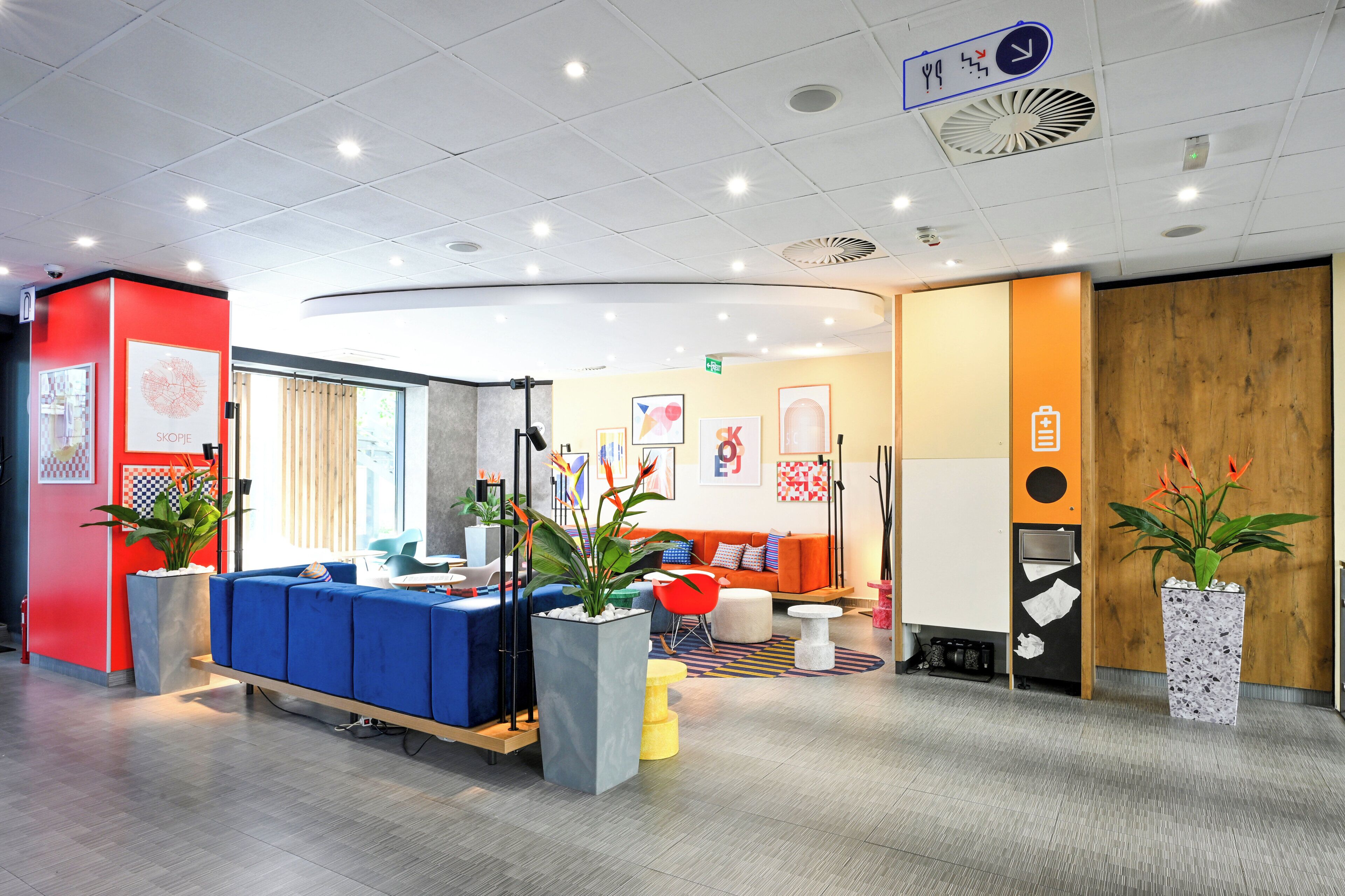 A modern reception area with a blue seating area, a wooden reception desk, and potted plants.