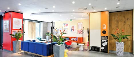 A modern reception area with a blue seating area, a wooden reception desk, and potted plants.