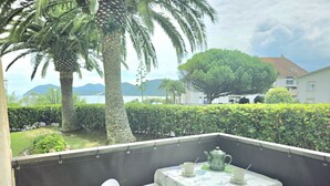 Un balcón con mesa y sillas, con vistas a un jardín ajardinado y una masa de agua.