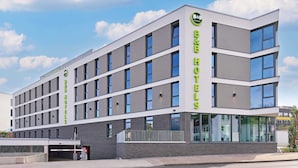 A modern B&B hotel with a flat facade, large windows, and a clear sky. - B&B HOTEL Arnsberg (Arnsberg)