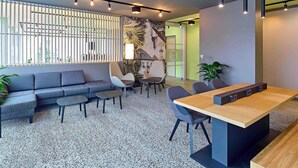 A modern office space with a sofa, chairs, a wooden table, and a patterned wall.