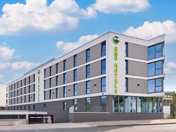A modern B&B hotel with a flat facade, large windows, and a clear sky. - B&B HOTEL Arnsberg (Arnsberg)