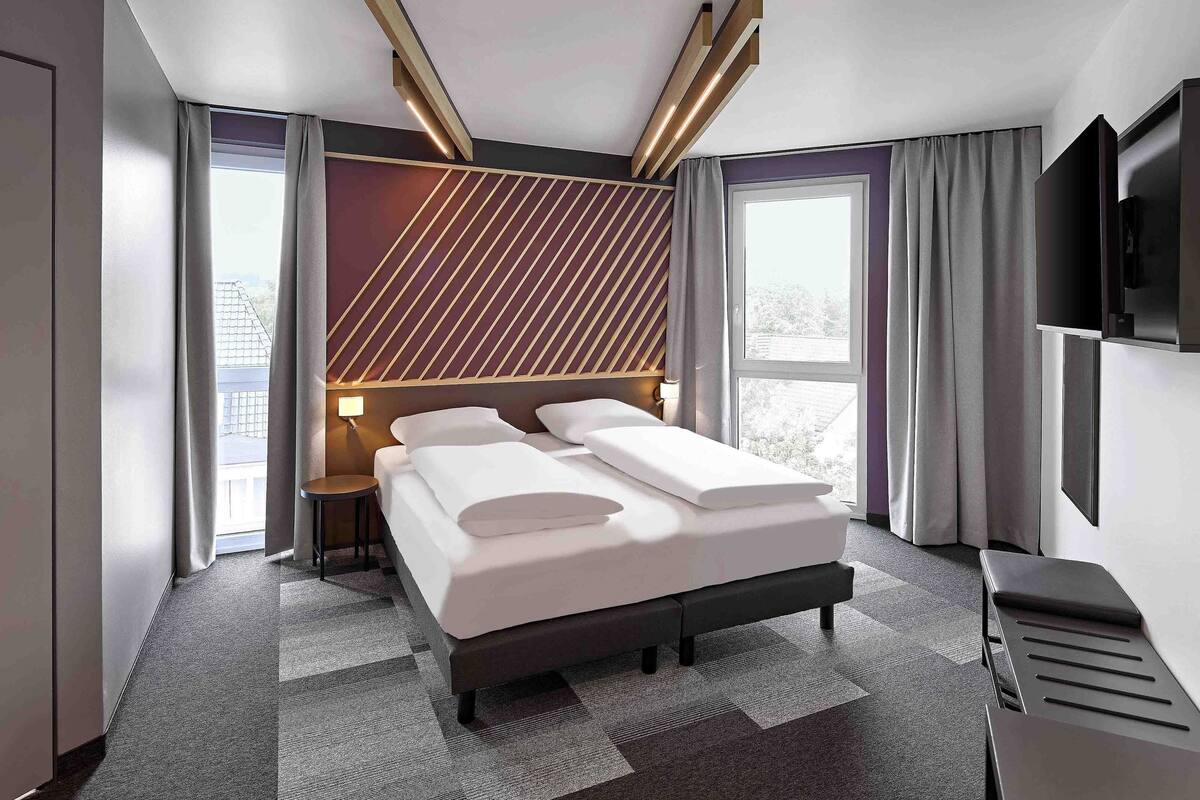 Ein modernes Hotelzimmer mit einem großen Bett, einem Fernseher und Blick ins Freie.