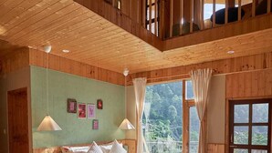 Un dormitorio espacioso con una cama grande, techo de madera y vistas al exterior.