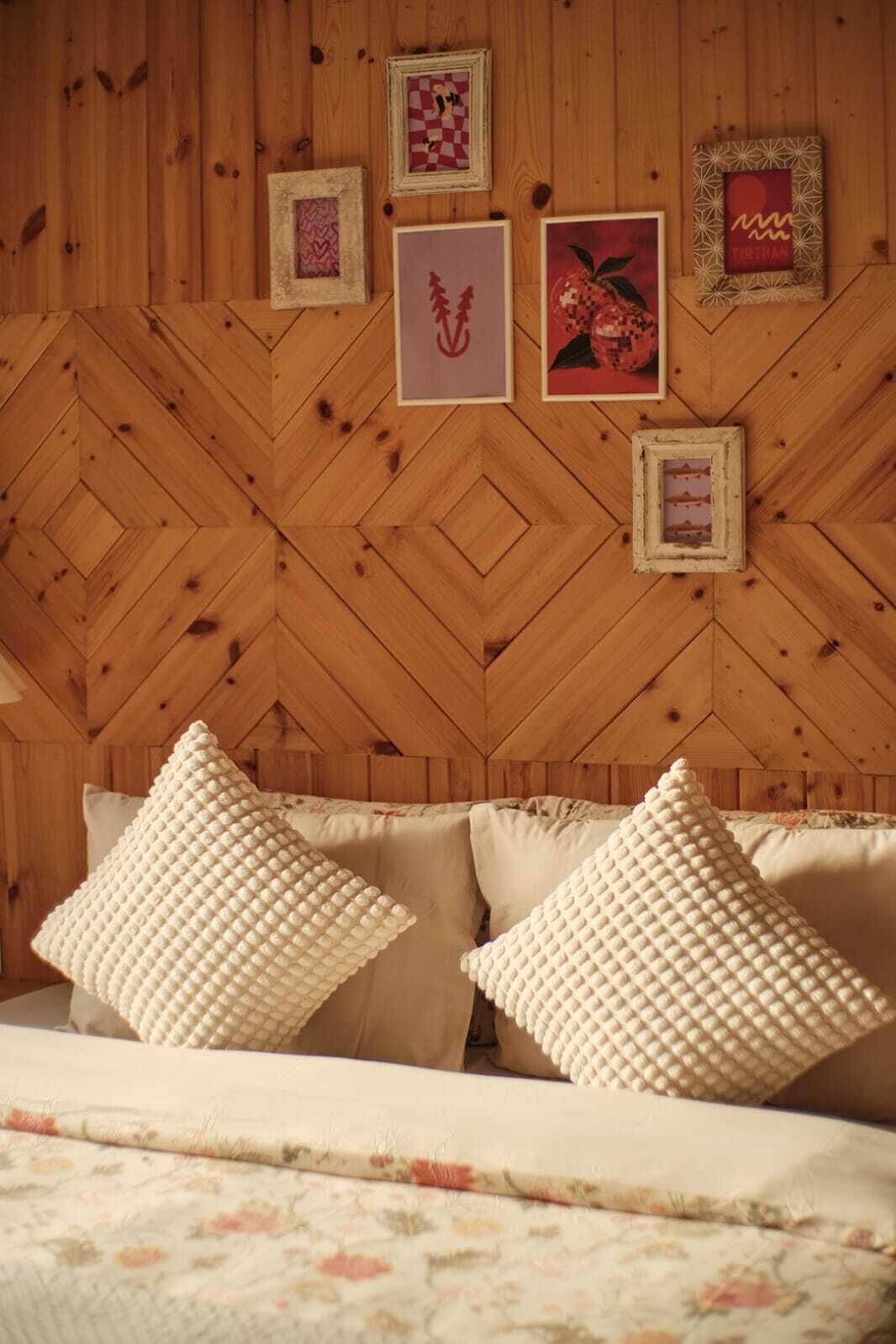 Una habitación con un patrón de pared de madera tipo espiga, una cama con ropa de cama floral y varias obras de arte enmarcadas en la pared.
