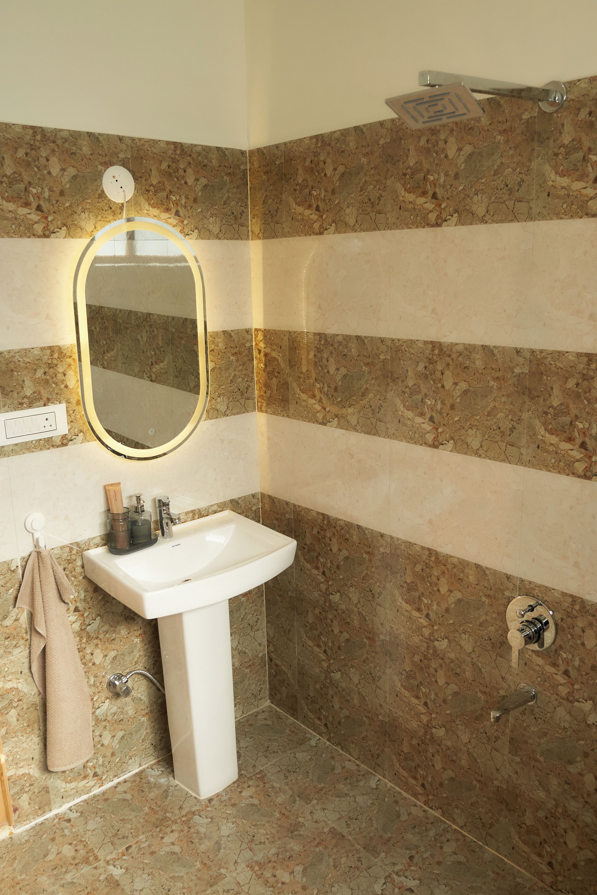 A bathroom with a white sink, a mirror with a light, and a shower.