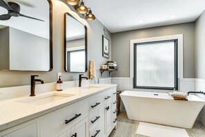A modern bathroom with a freestanding bathtub, a double sink vanity, and a large mirror. - 2 Blocks to Golf Course: Spacious Tampa Home! (Tampa)