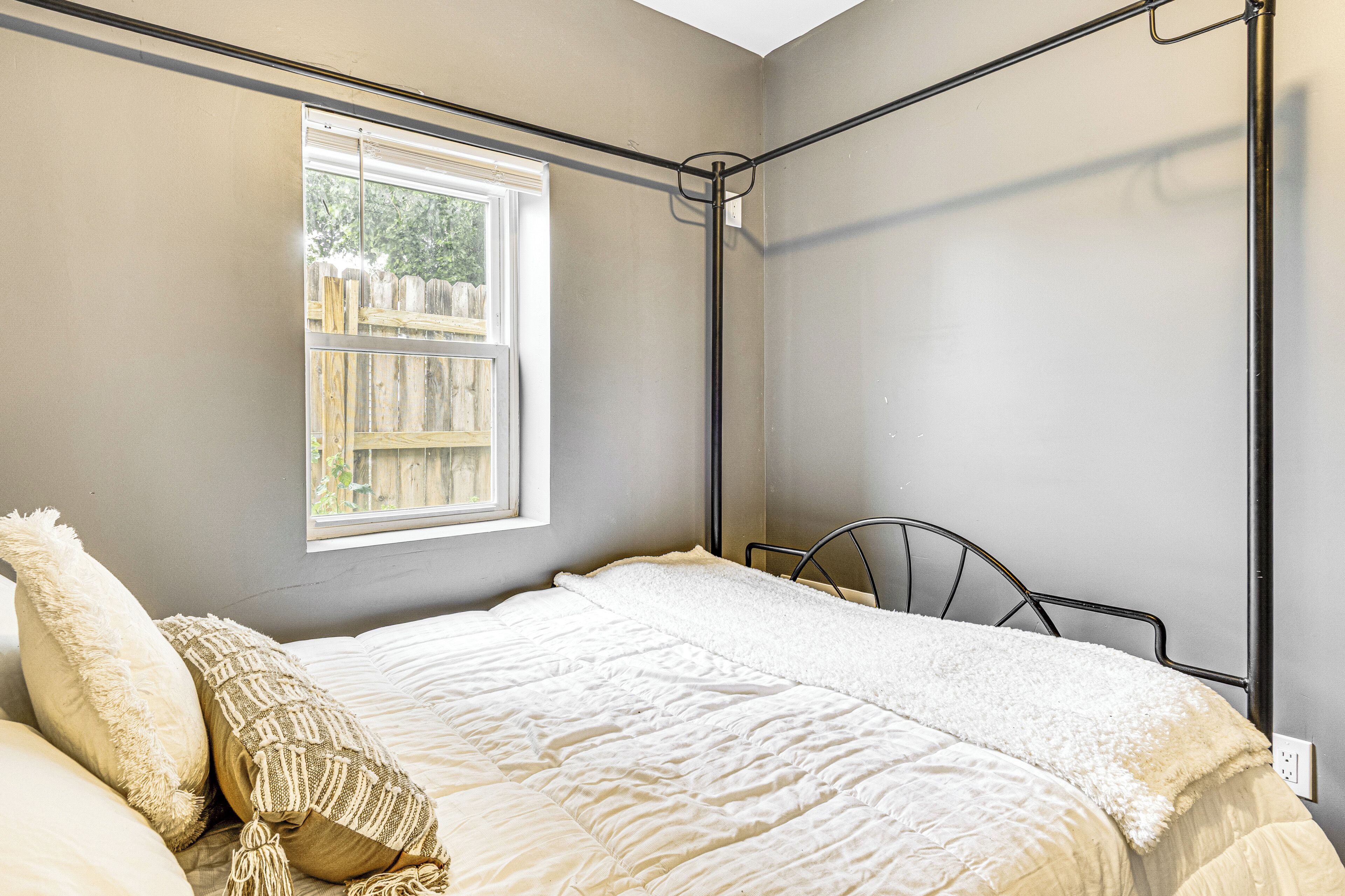 A bedroom with a bed, a window, and a metal headboard.