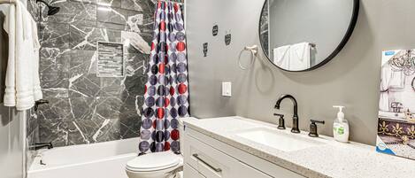A modern bathroom with a bathtub, toilet, and vanity.