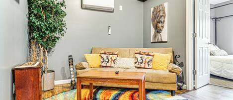 A living room with a sofa, coffee table, and a colorful rug.