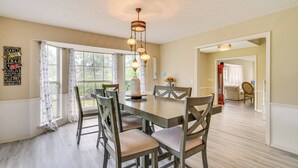 A dining room with a large table, chairs, and a chandelier. There are curtains on the windows, and a sign on the wall. - Private Pool & Yard: Family Retreat in Cape Coral (Cape Coral)