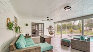 A covered patio area with wicker furniture, a ceiling fan, and a view of a swimming pool. - Private Pool & Yard: Family Retreat in Cape Coral (Cape Coral)