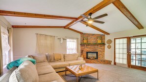 A living room with a sectional sofa, a wooden ceiling, a fireplace, and a sliding glass door. - Private Pool & Yard: Family Retreat in Cape Coral (Cape Coral)