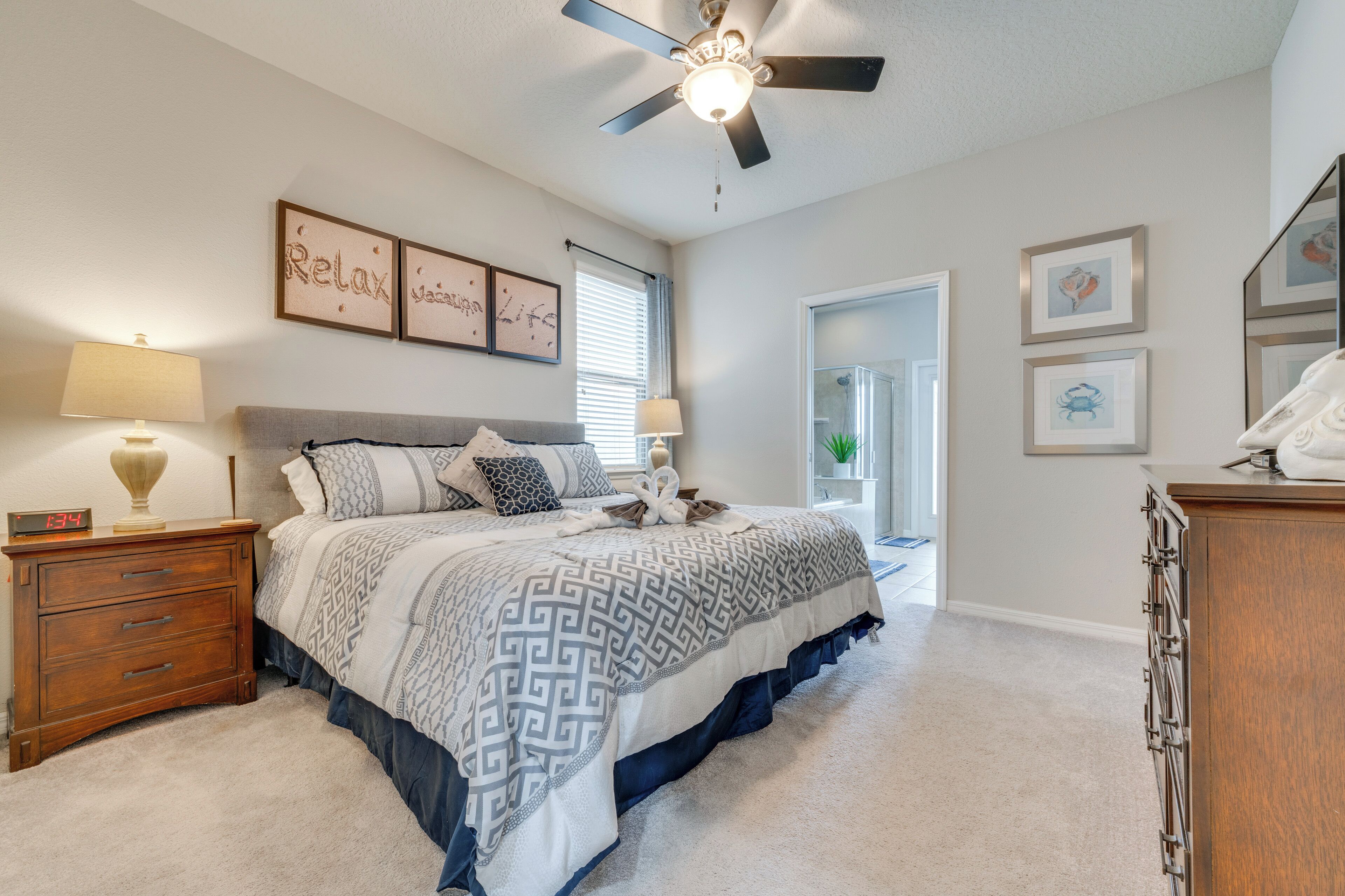 A bedroom with a bed, nightstands, a ceiling fan, and wall art.
