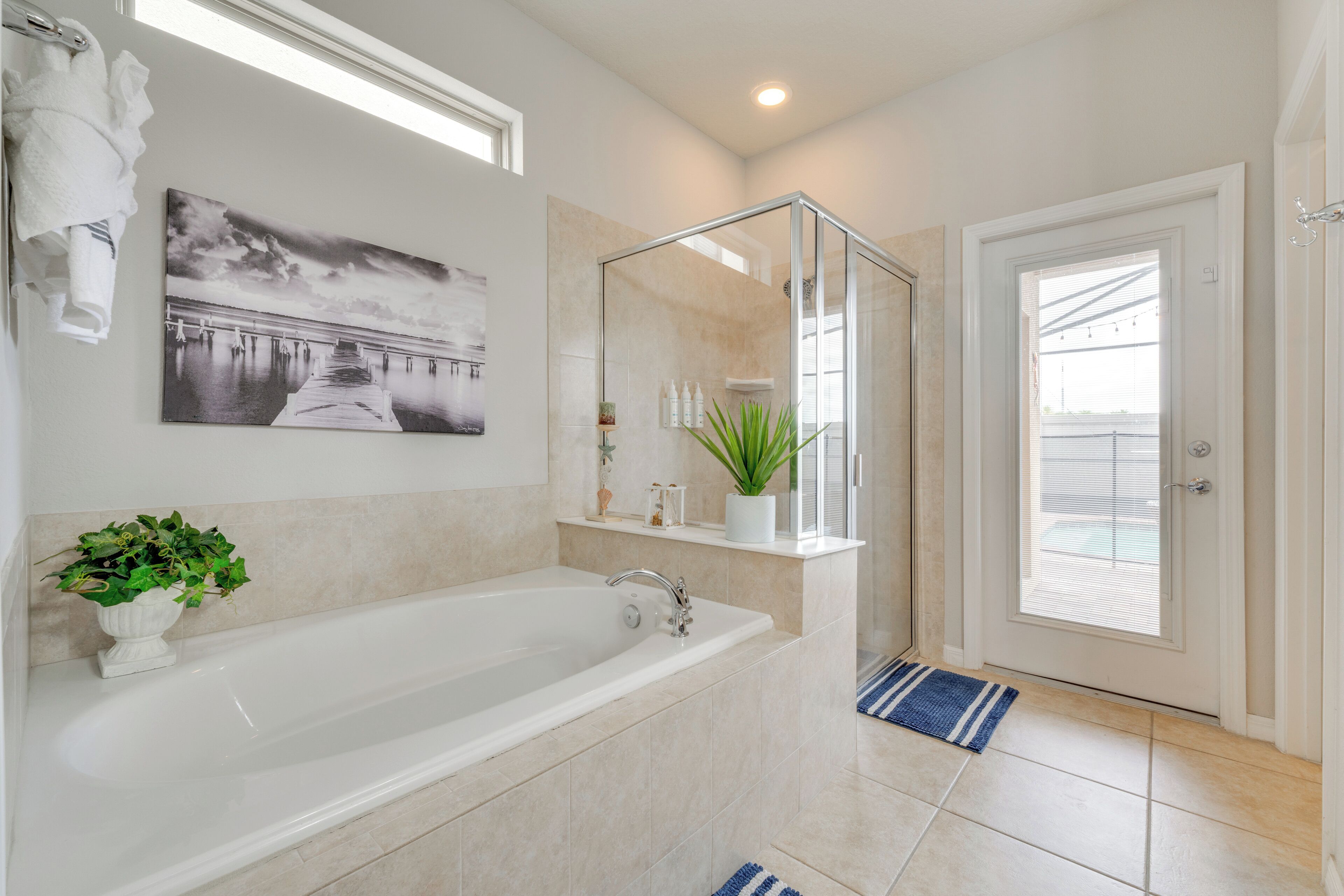 Une salle de bain moderne dotée d’une grande baignoire, d’une douche à parois de verre et d’une porte donnant sur un balcon.