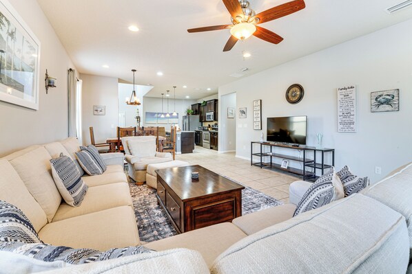 A spacious living room with a large sofa set, a coffee table, and a television. - Pool, Game Room & More! Resort Home 9 Mi to Disney (Kissimmee)