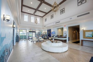 A spacious lobby with a central seating area, a reception desk, and a large chandelier.