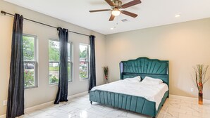 Ein Schlafzimmer mit einem Bett, einem Deckenventilator und großen Fenstern.