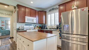 A modern kitchen with wooden cabinets, a stainless steel refrigerator, and a central island.