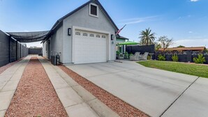A single-story house with a white garage door, a covered driveway, and a small patio area with outdoor furniture.