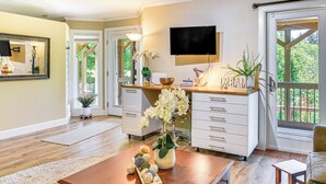 A well-lit living room with a wooden coffee table, a white sofa, and a TV mounted on the wall. - Backs to Wetlands: Tranquil Beaverton Retreat! (Beaverton)